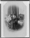 Marian Hubbard (1880–1962) und Elsie May Bell (1878-1964) mit Gouvernante, Schwarz-Weiß-Photographie, ca. 1885, unbekannter Photograph; Bildquelle: Library of Congress, Prints and Photographs Division Washington, Gilbert H. Grosvenor Collection of Photographs of the Alexander Graham Bell Family, Reproduction Number: LC-USZ62-122254, http://www.loc.gov/pictures/item/00649940/.