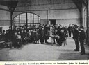 "Auswanderer vor dem Comitè des Hilfsvereins der Deutschen Juden in Hamburg [in den Auswandererhallen der Hamburg-Amerika Linie]", unbekannter Photograph, 1907; Bildquelle: Sechster Geschäftsbericht des Hilfsvereins der Deutschen Juden (1907), Berlin 1908, S. 112.