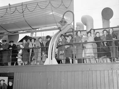 W. J. Hynes: War brides and their children en route to Canada, Schwarz-Weiß-Fotografie, 1944; Bildquelle: http://collectionscanada.gc.ca/pam_archives/index.php?fuseaction=genitem.displayItem&lang=eng&rec_nbr=3210426&rec_nbr_list=3210426,3352285,3523566,3352282,3204397,3204398,3193079. Gemeinfrei.